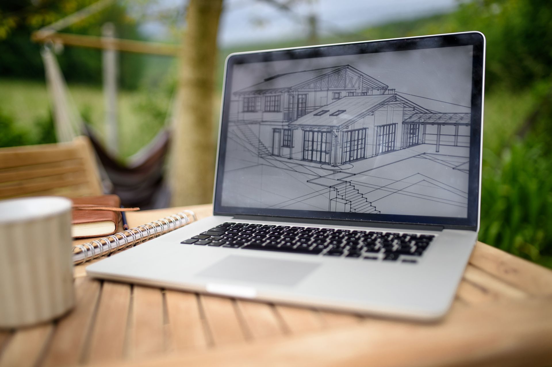 A laptop computer is sitting on a wooden table with a drawing of a house on the screen.