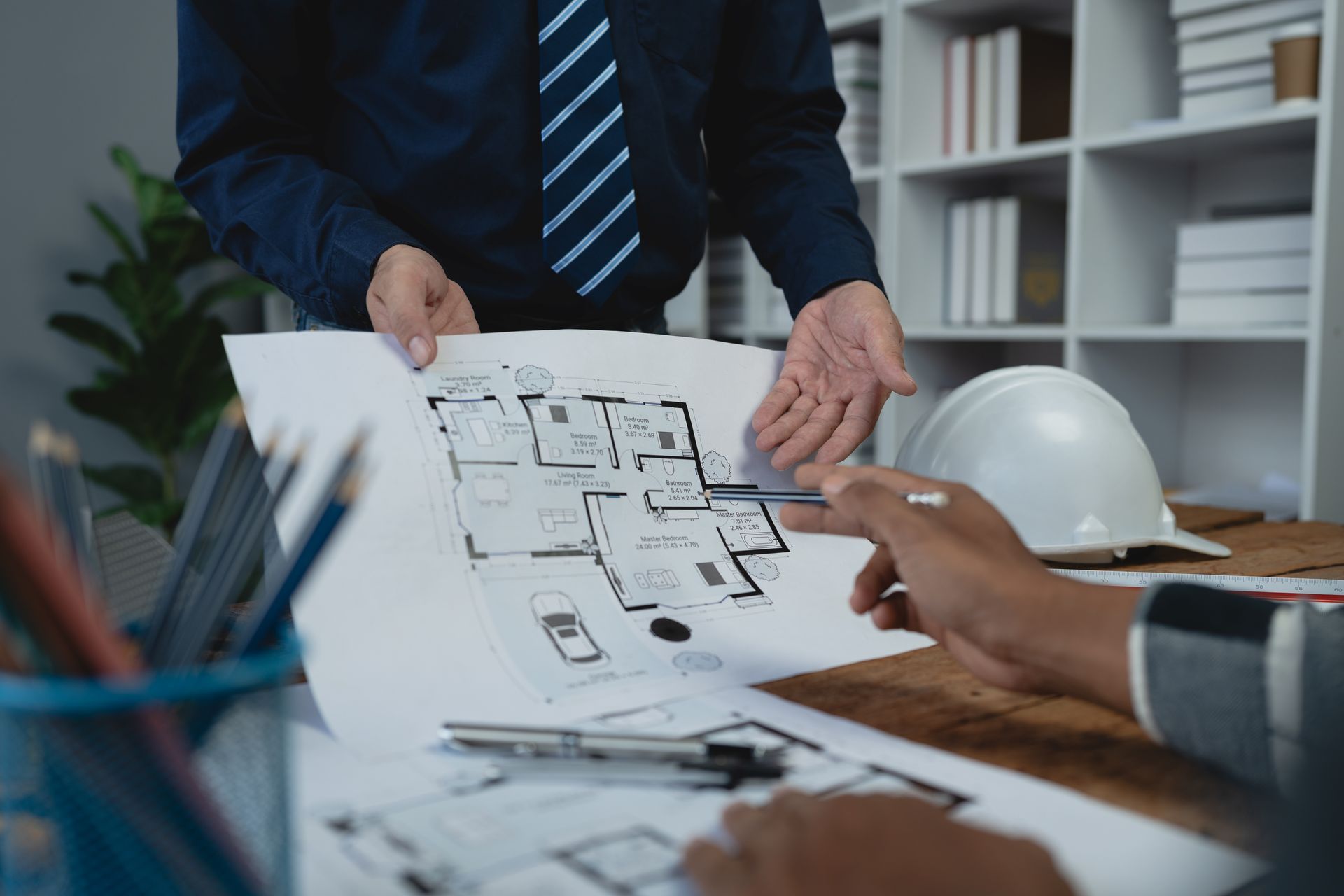 A group of people are sitting at a table looking at a blueprint.