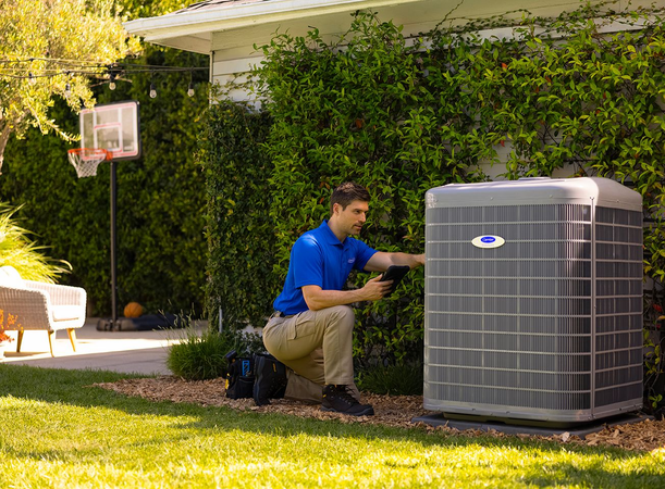 Technician testing HVAC wiring with a yellow multimeter on an outdoor unit