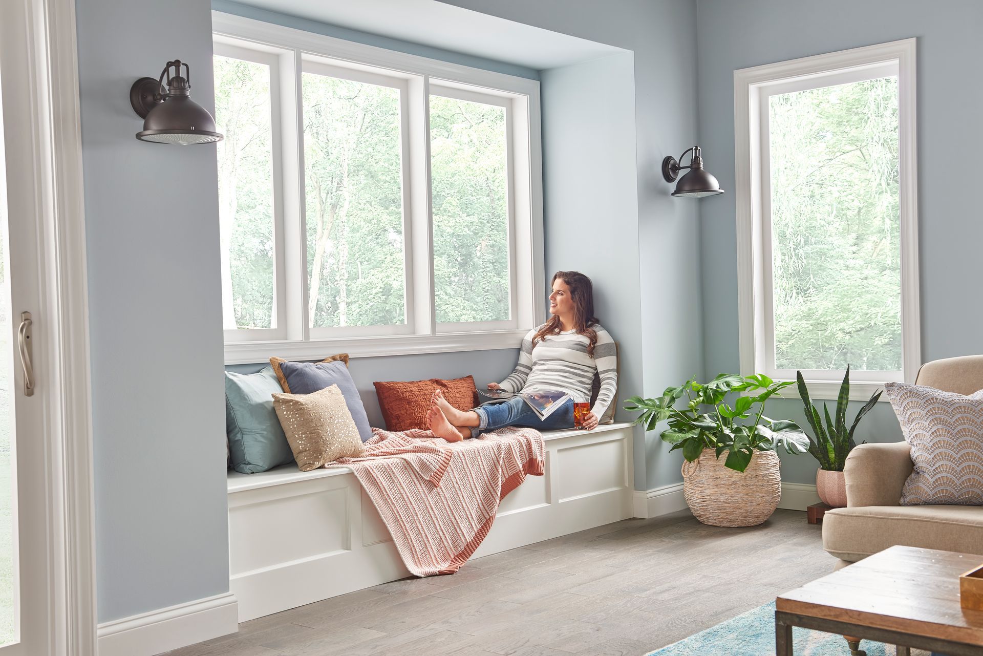Home office with desk, chair, shelves, plants, and a wall-mounted TV in a bright room