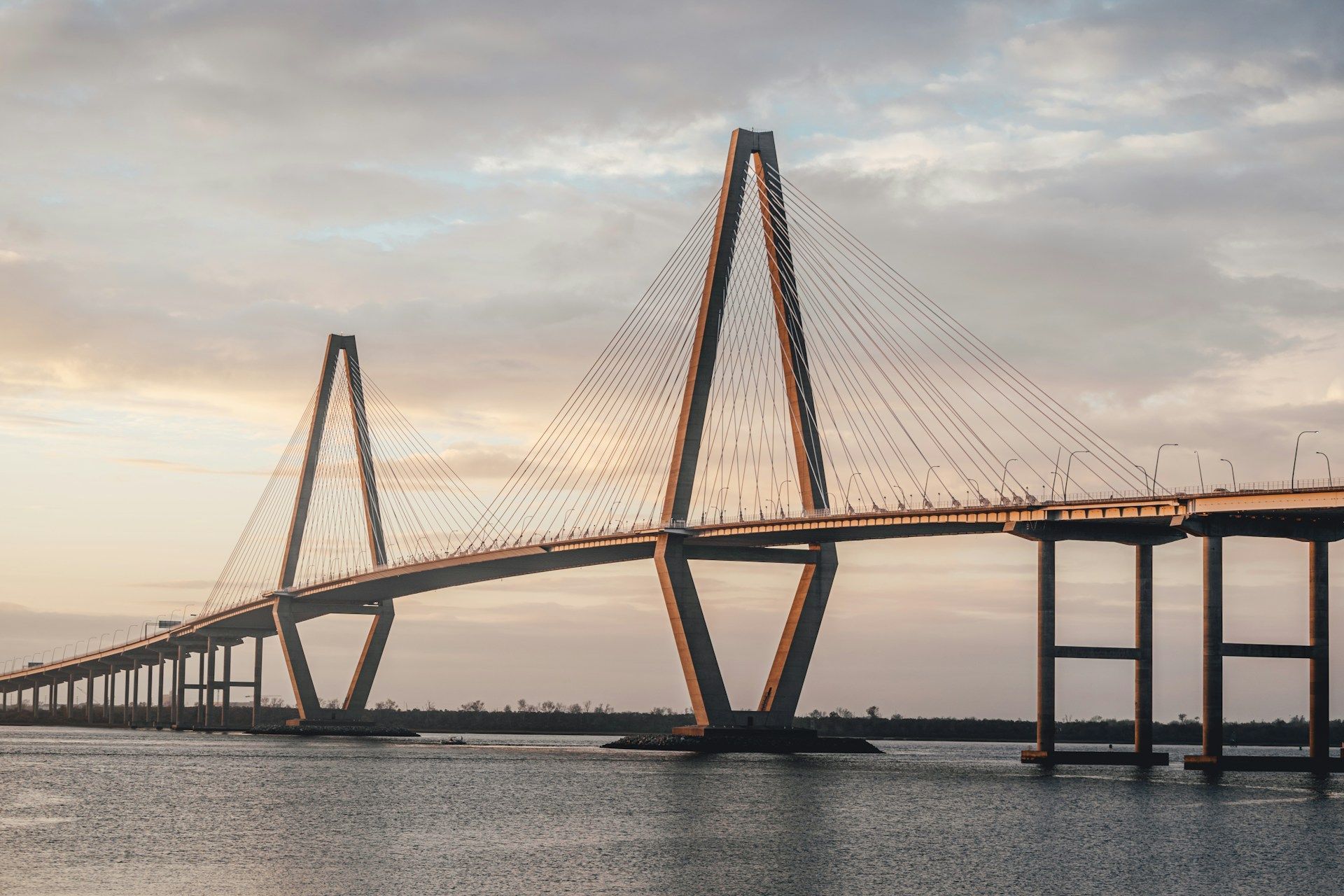 Cable-stayed bridge over water at sunset with a long span and two towers