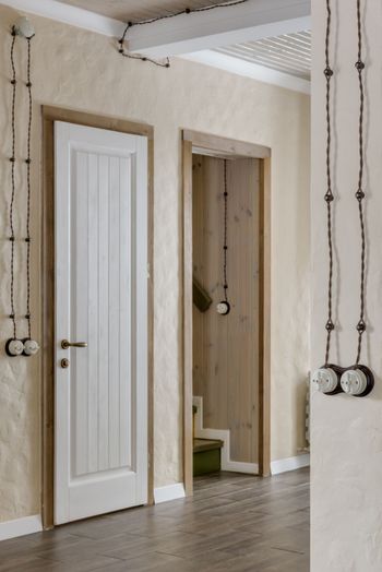 Hallway with two white doors, beige walls, wood floor, and exposed hanging wiring.