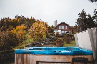 Backyard hot tub with autumn trees and a house in the background