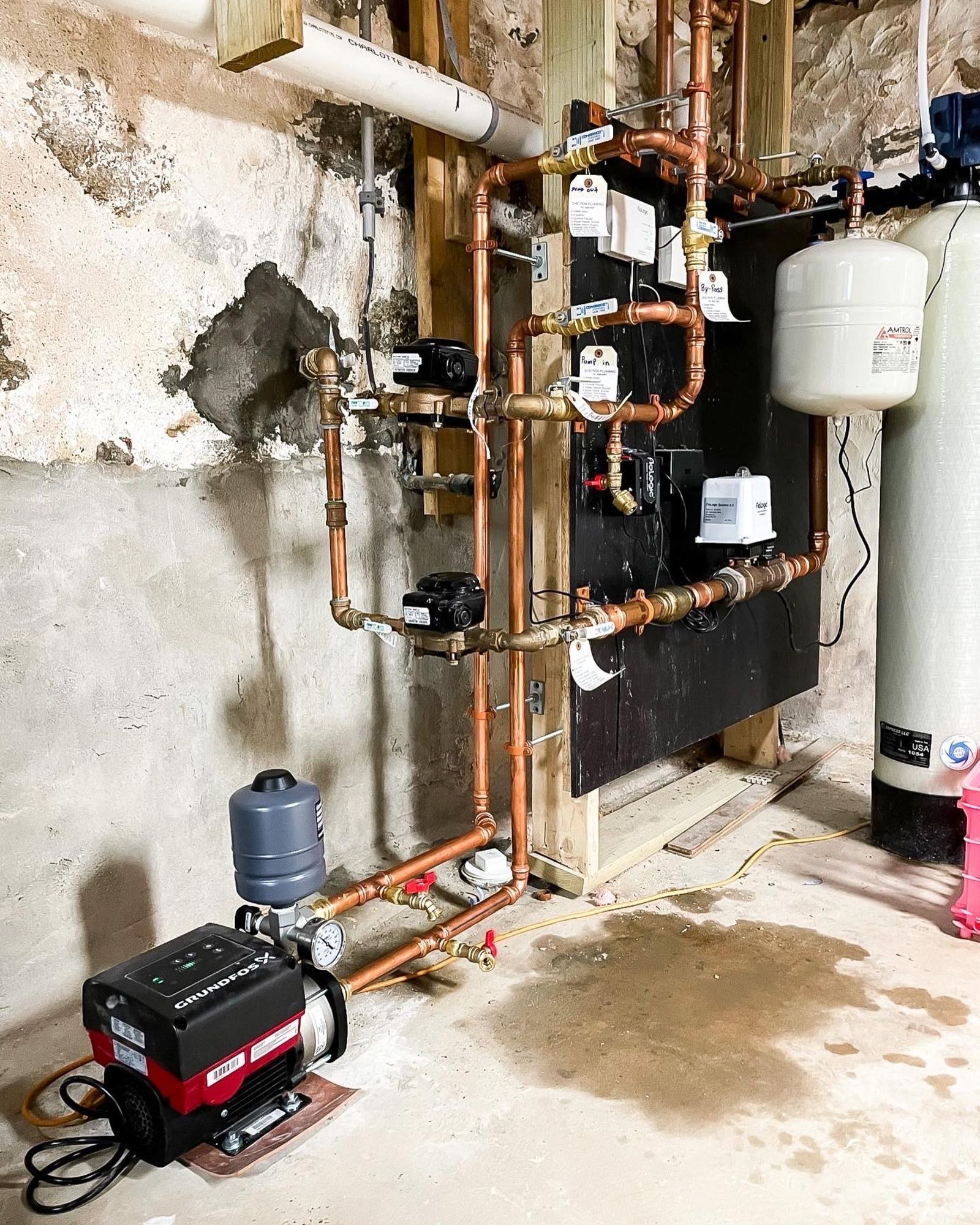 A room with a lot of pipes and a water heater.