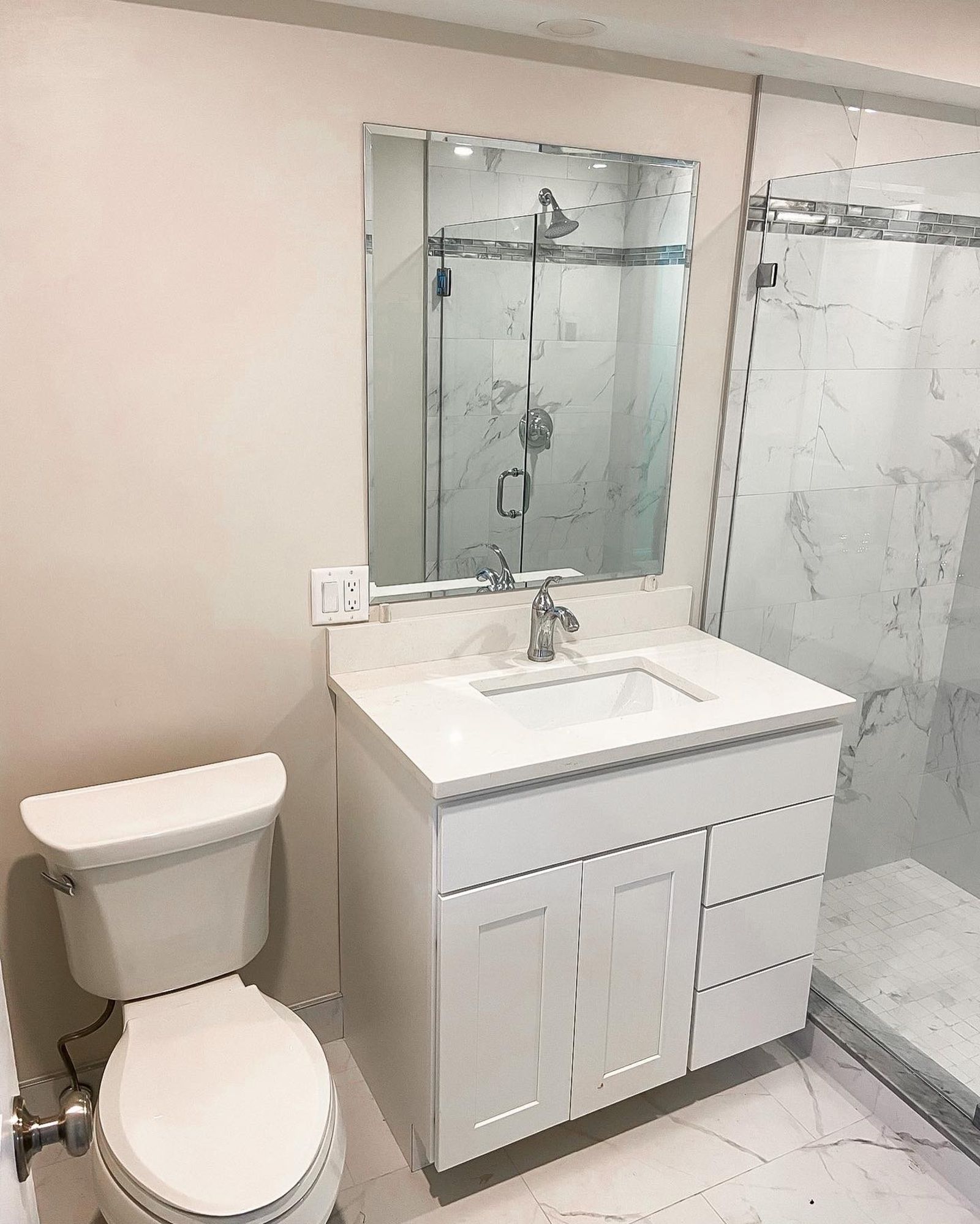 A bathroom with a toilet , sink , mirror and shower.