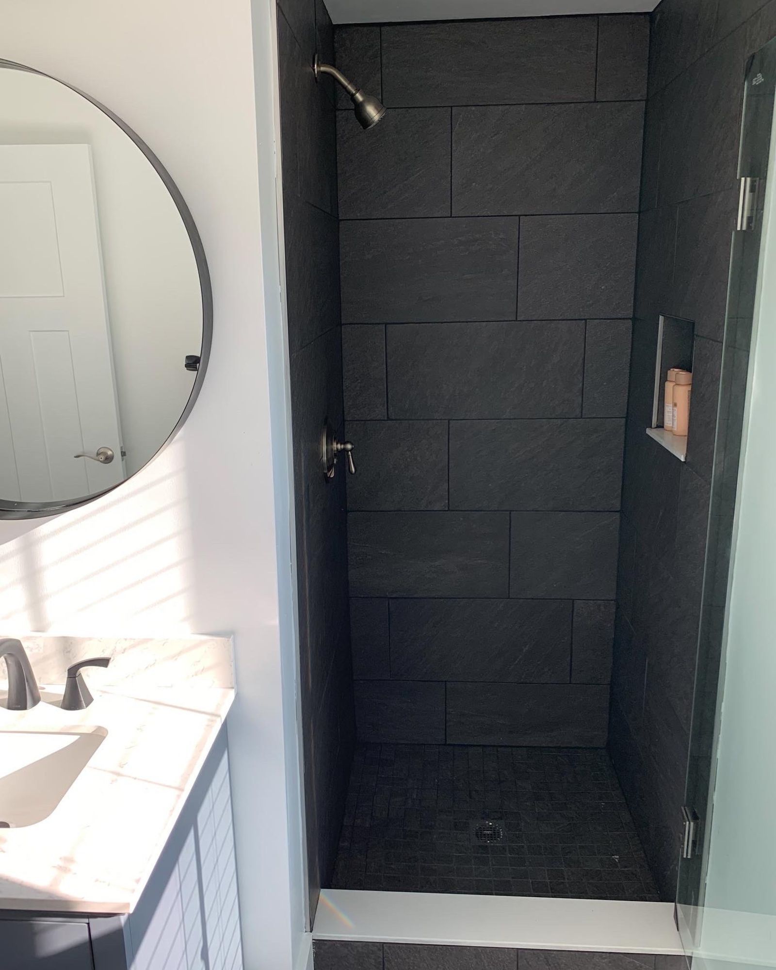A bathroom with a shower , sink and mirror