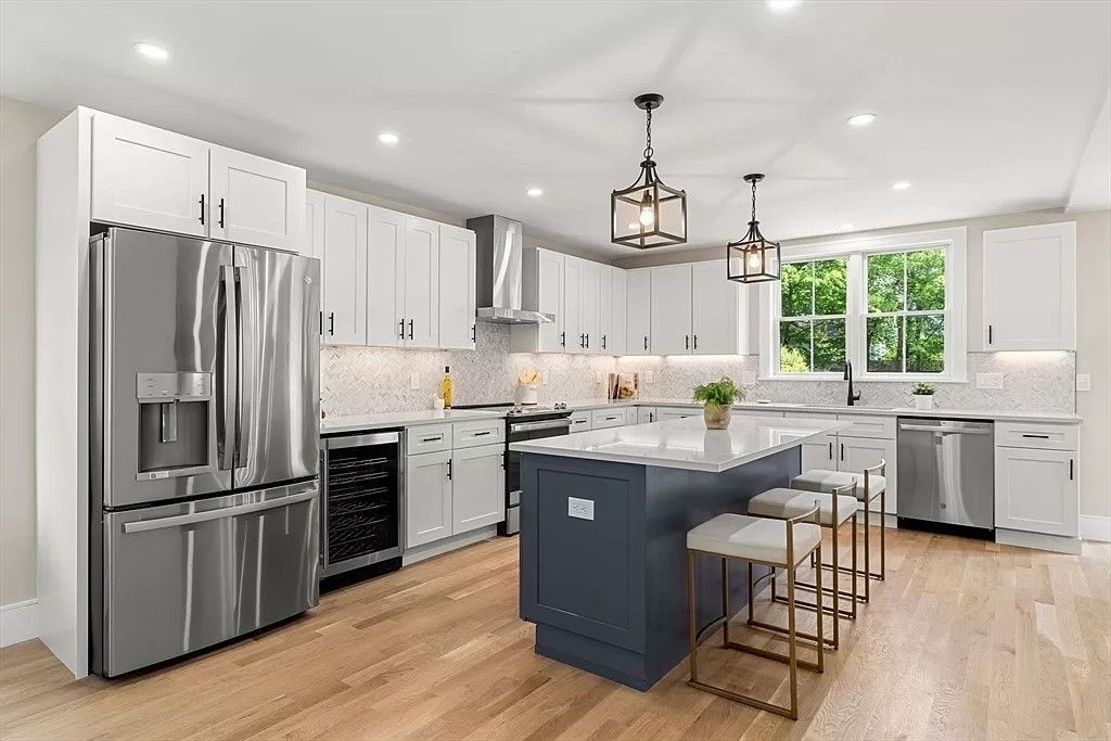 A kitchen with white cabinets , stainless steel appliances , and a large island.