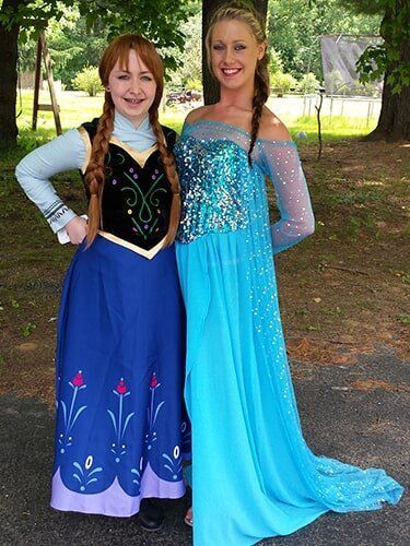 Two women dressed as Anna and Elsa from Frozen posing outside.