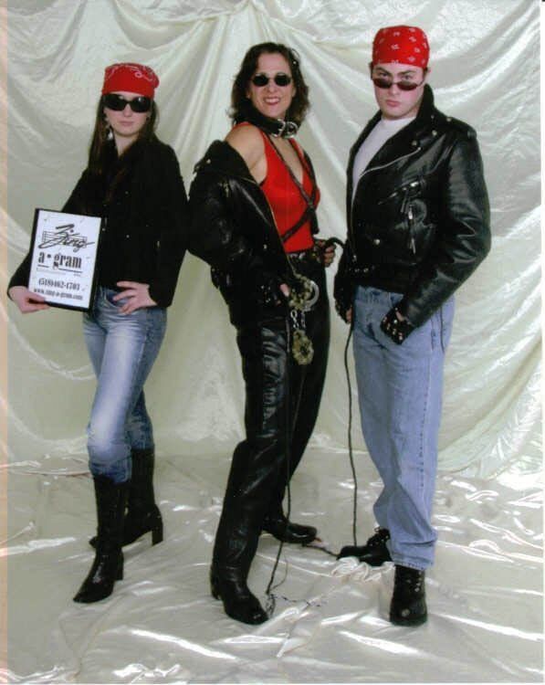 Three people in biker attire pose in front of a white backdrop.