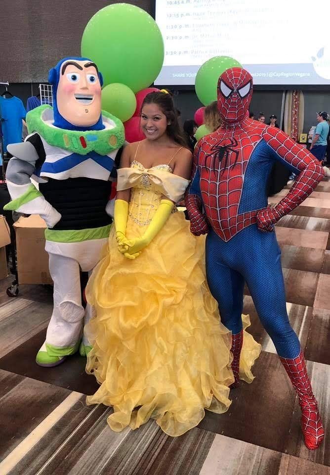 Buzz Lightyear, Belle, and Spider-Man posing together, with green balloons in the background.