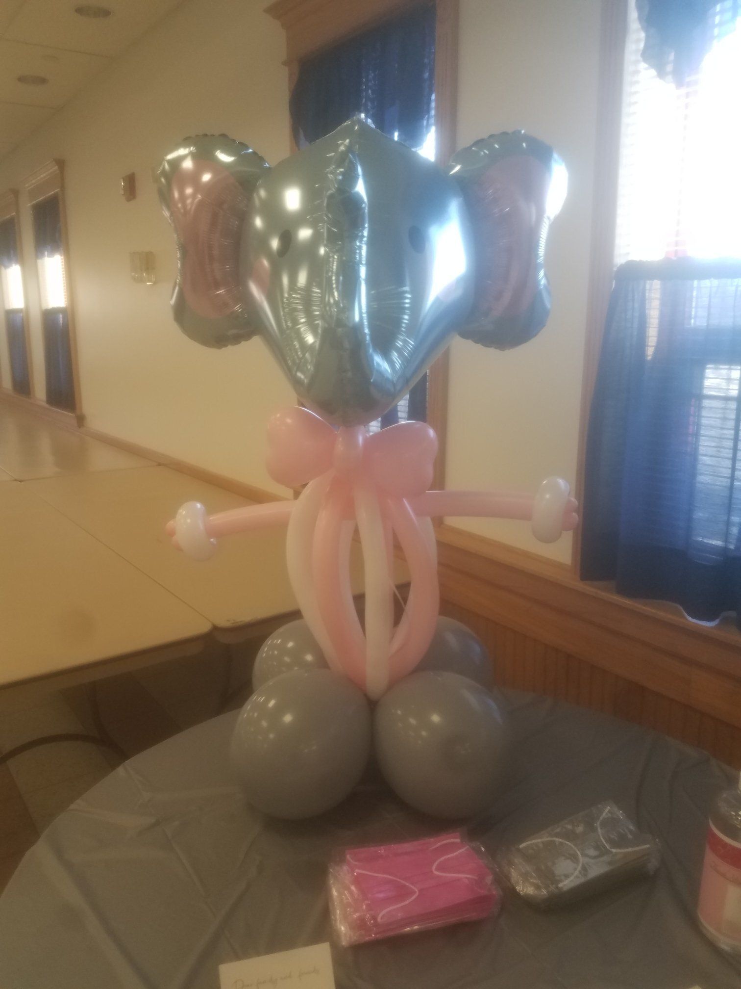 Balloon elephant sculpture with pink bow on a table, with tools and decor.