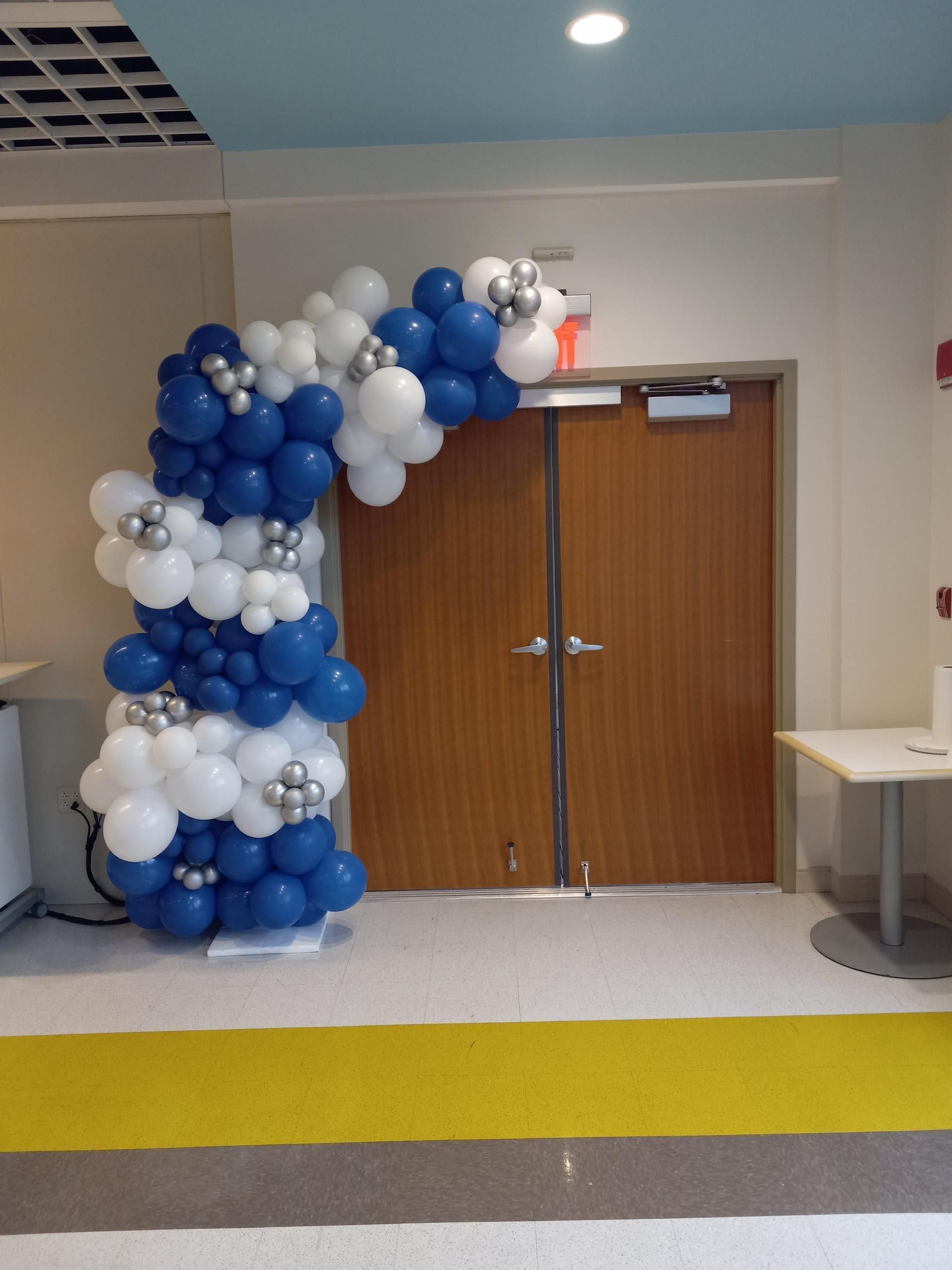 Balloon arch in blue, white, and silver decorates a doorway.