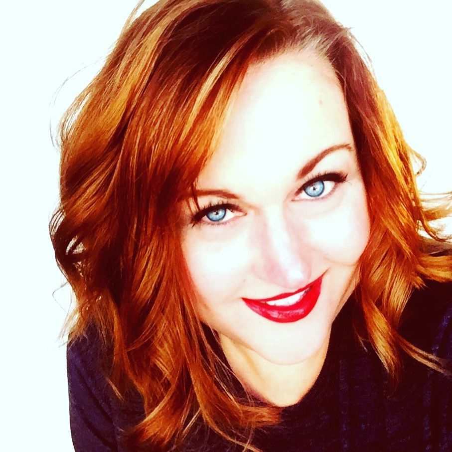 A woman with red hair and blue eyes smiles for the camera