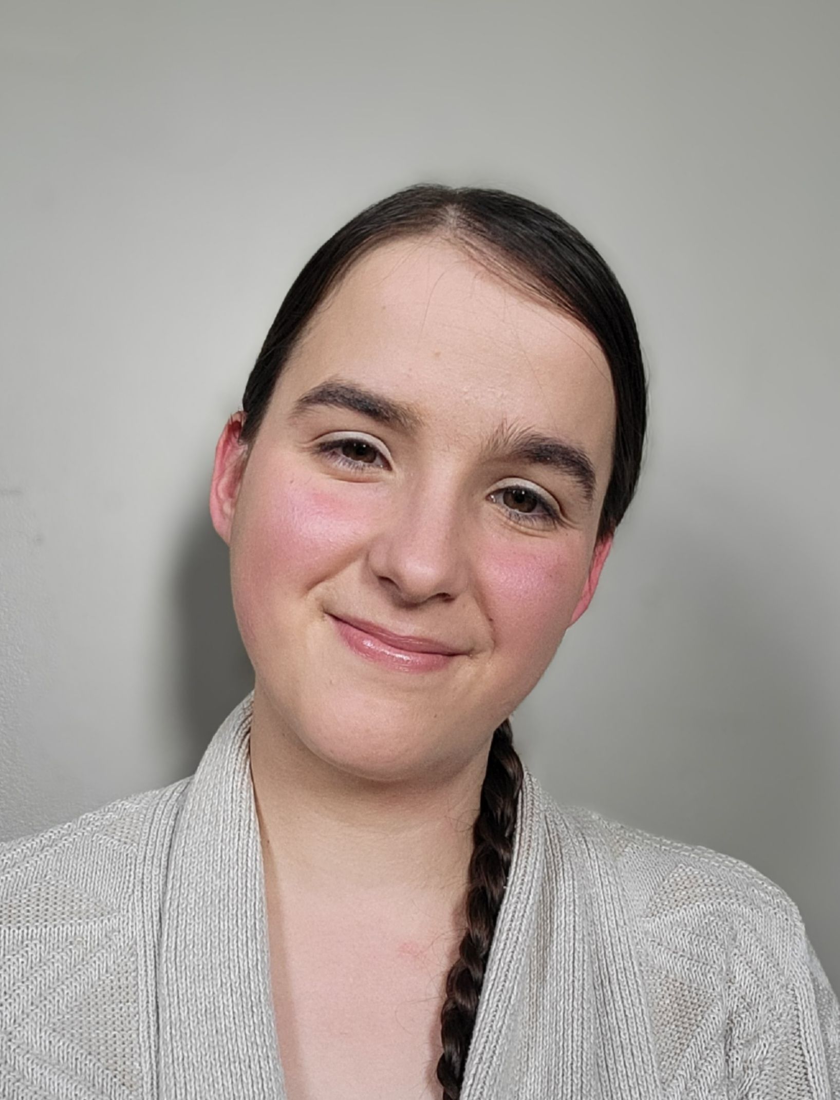 A woman is smiling for the camera and wearing a braided ponytail.