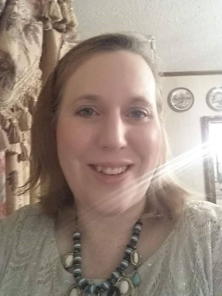 A woman wearing a necklace is smiling for the camera.