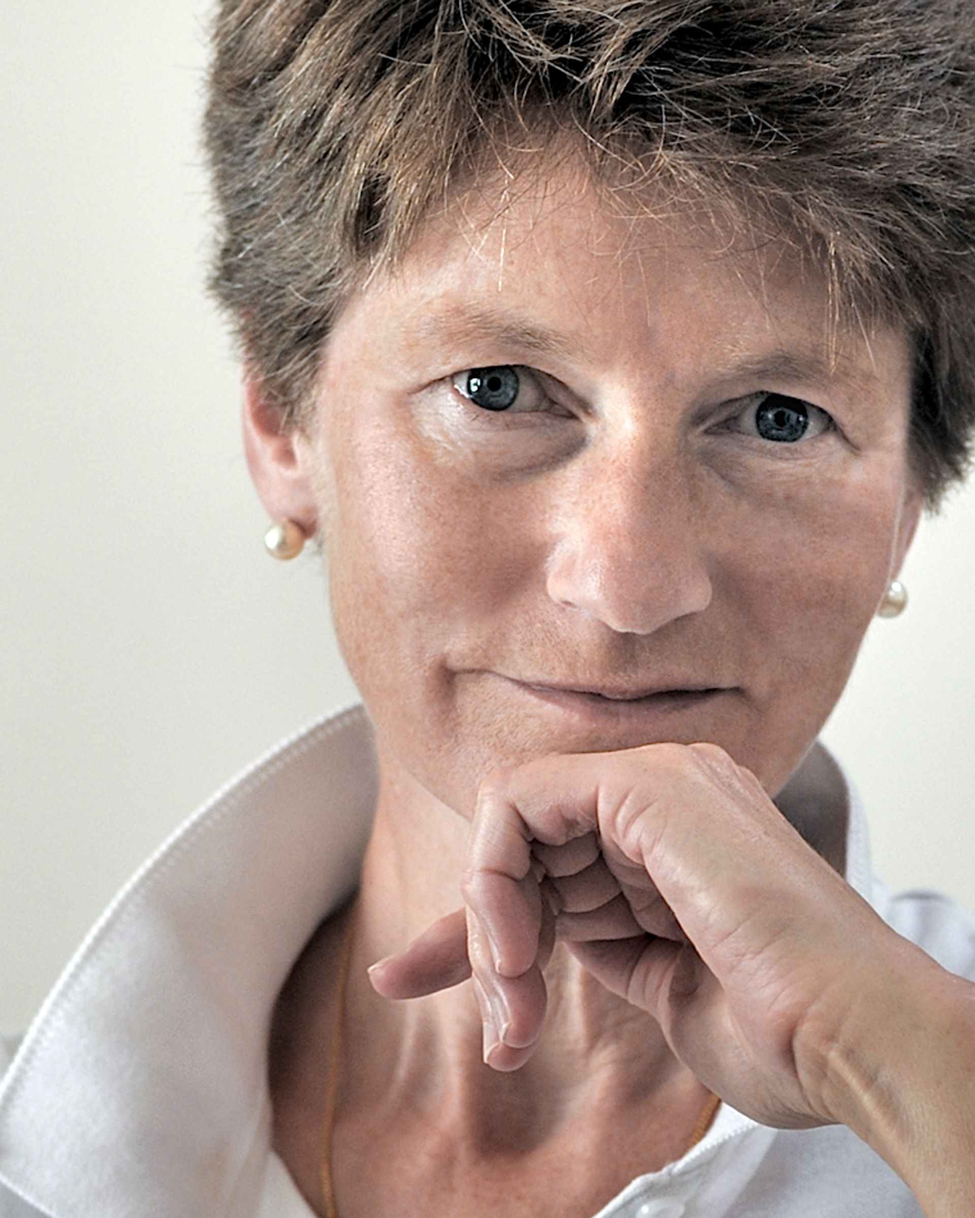 A close up of a woman 's face with her hand on her chin.