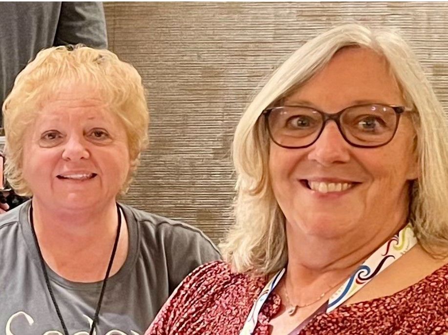 Two women are posing for a picture together and smiling for the camera.