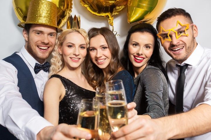 Group toasting with champagne at a festive party, smiling under gold balloons and star-shaped glasses