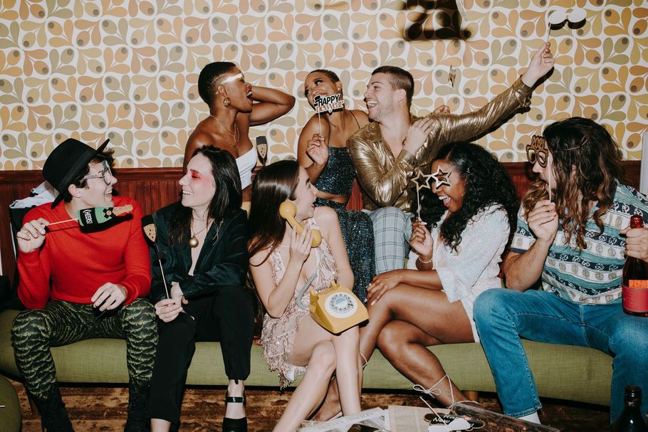 Group of people chatting and posing on a couch in a colorful room with patterned wallpaper