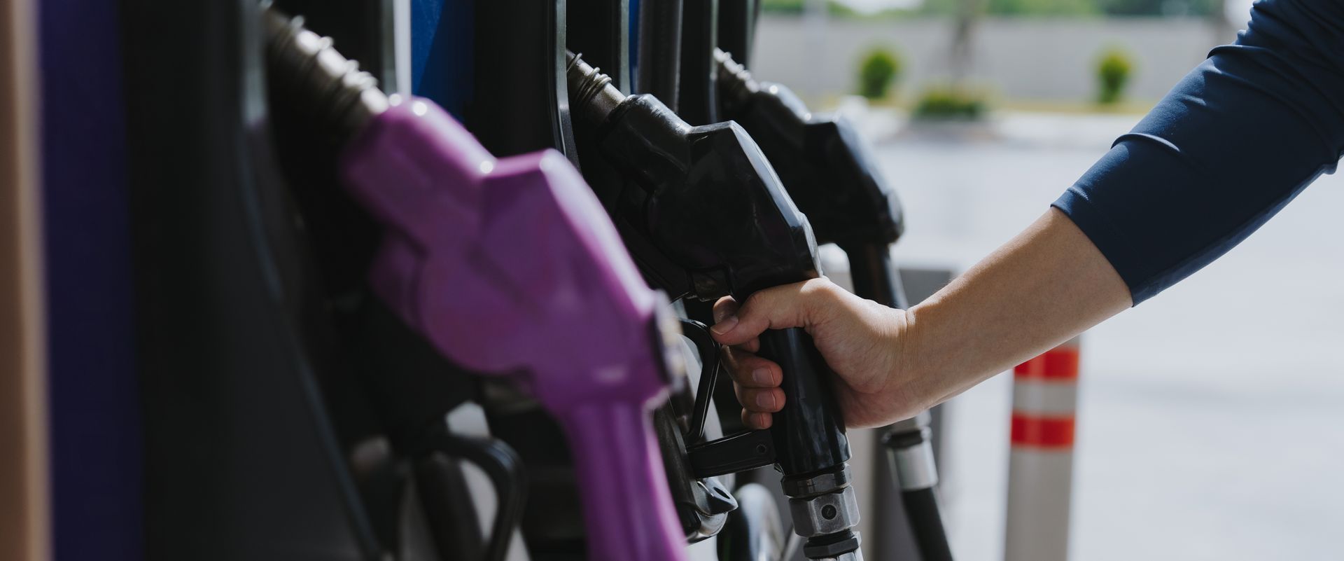 Fuel supplier pumping diesel fuel at gas station with close-up of hand holding nozzle.
