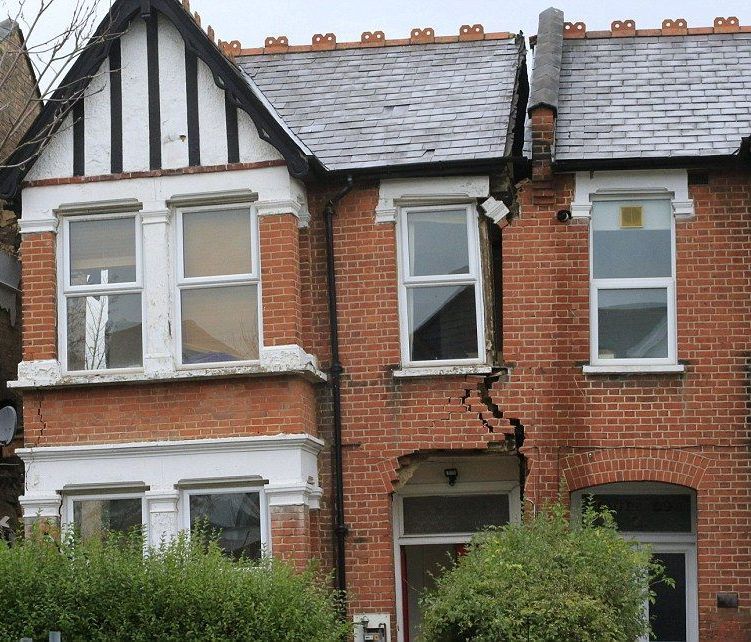 Two-story brick houses with a large vertical crack, affecting the structure and roof, and causing damage.
