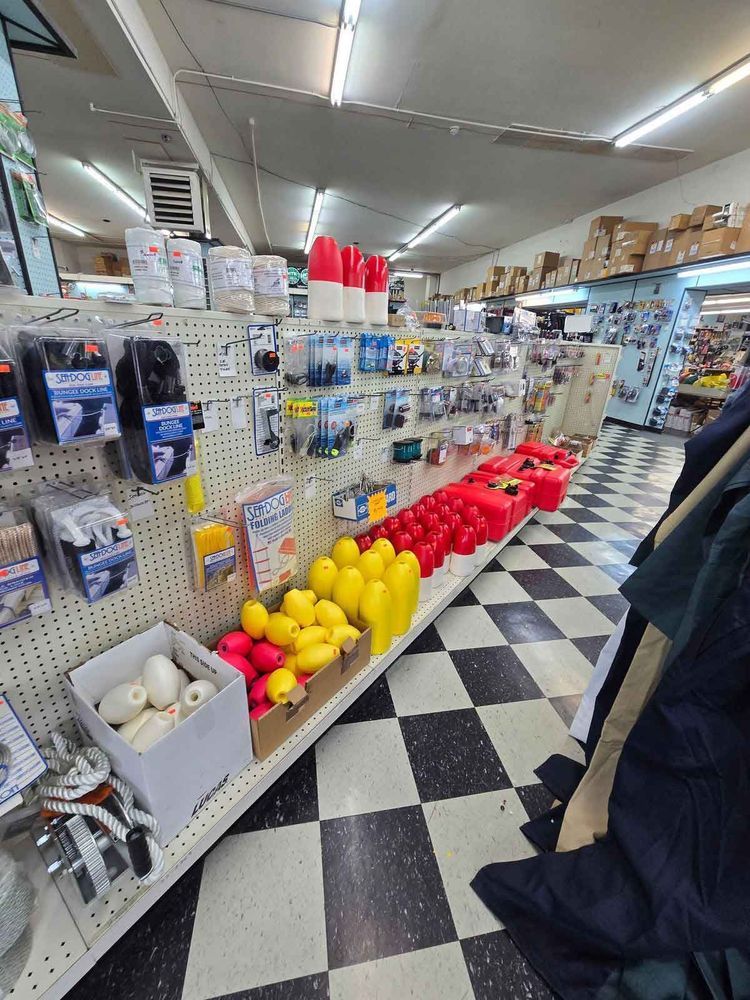 A store aisle with black and white checkered floor, shelves of various red and yellow buoys, and other marine supplies.