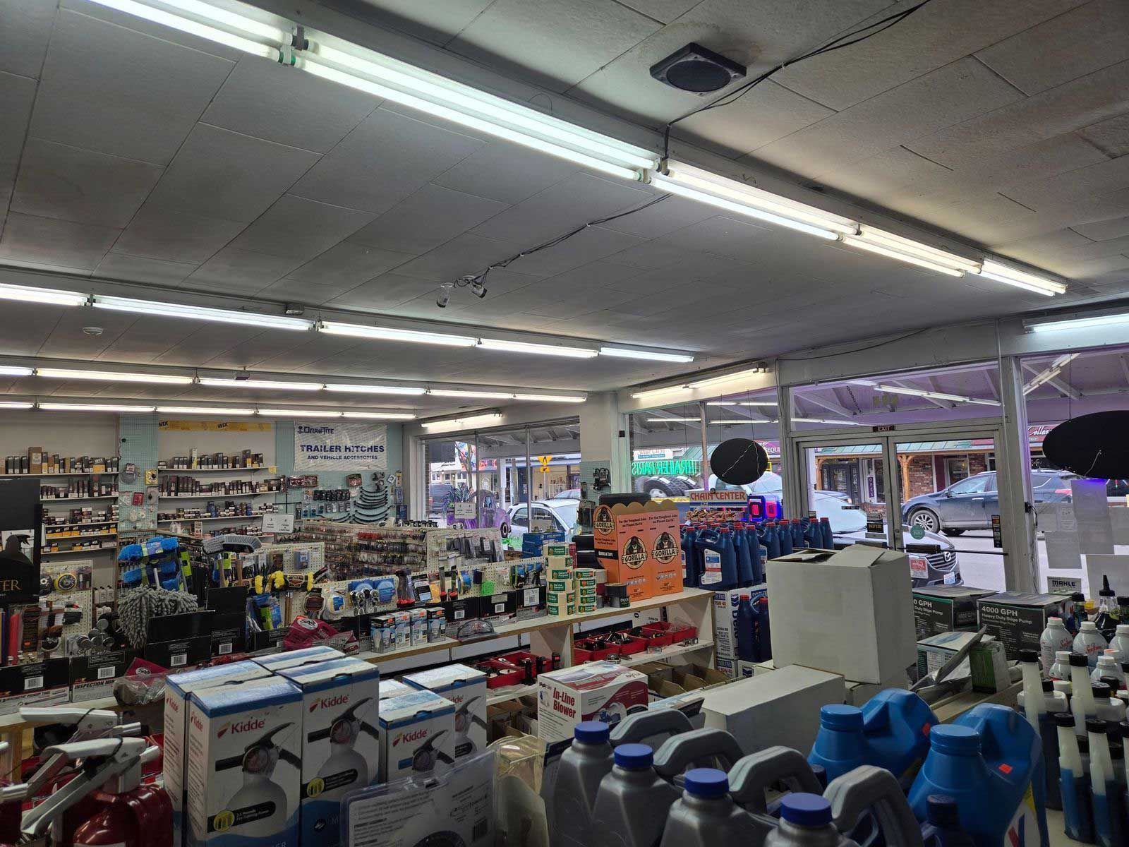 Inside of a store, shelves stocked with various products. Fluorescent lights illuminate the space.