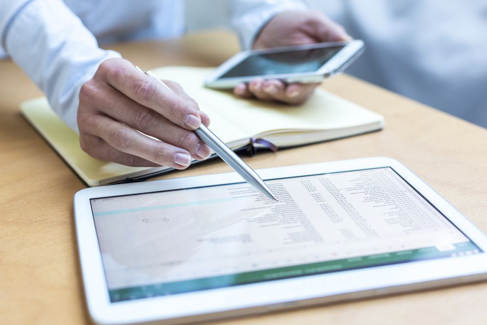 Hands using a stylus on a tablet beside a smartphone on a desk — Qwerty Plus in Gosford, NSW