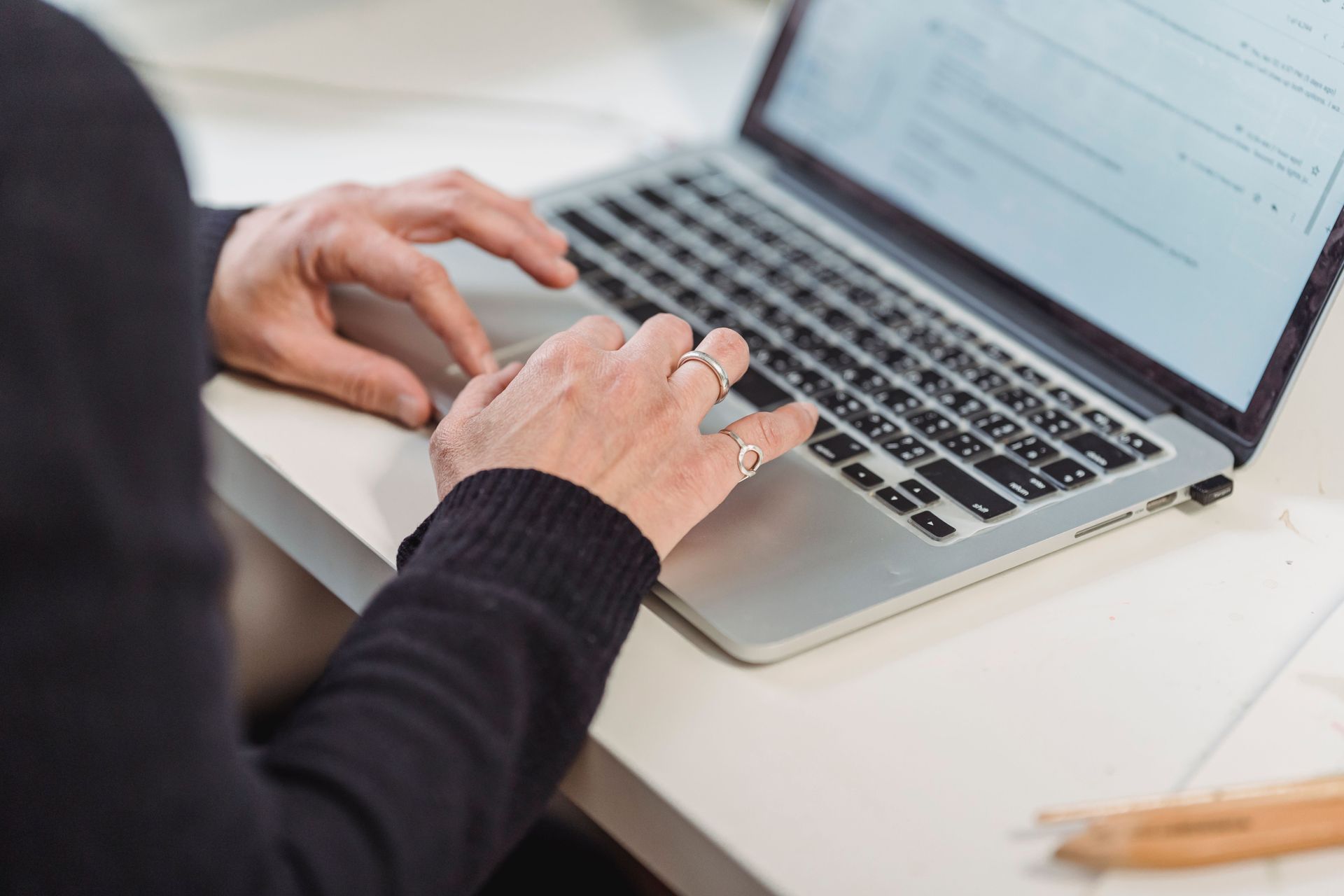 Person typing at a laptop beside papers and a notebook on a desk in an office setting — Qwerty Plus in Gwandalan, NSW