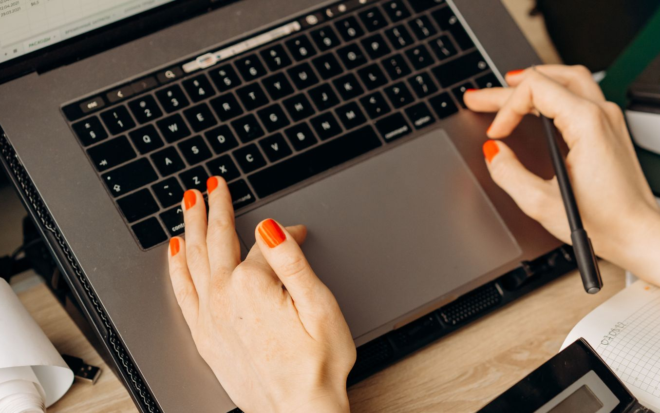 Hands sorting receipts beside a calculator and laptop on a desk — Qwerty Plus in Wyong, NSW