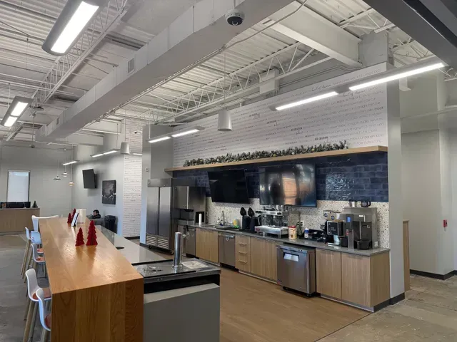 Modern commercial kitchen with stainless steel appliances, wood counters, and bright overhead lighting