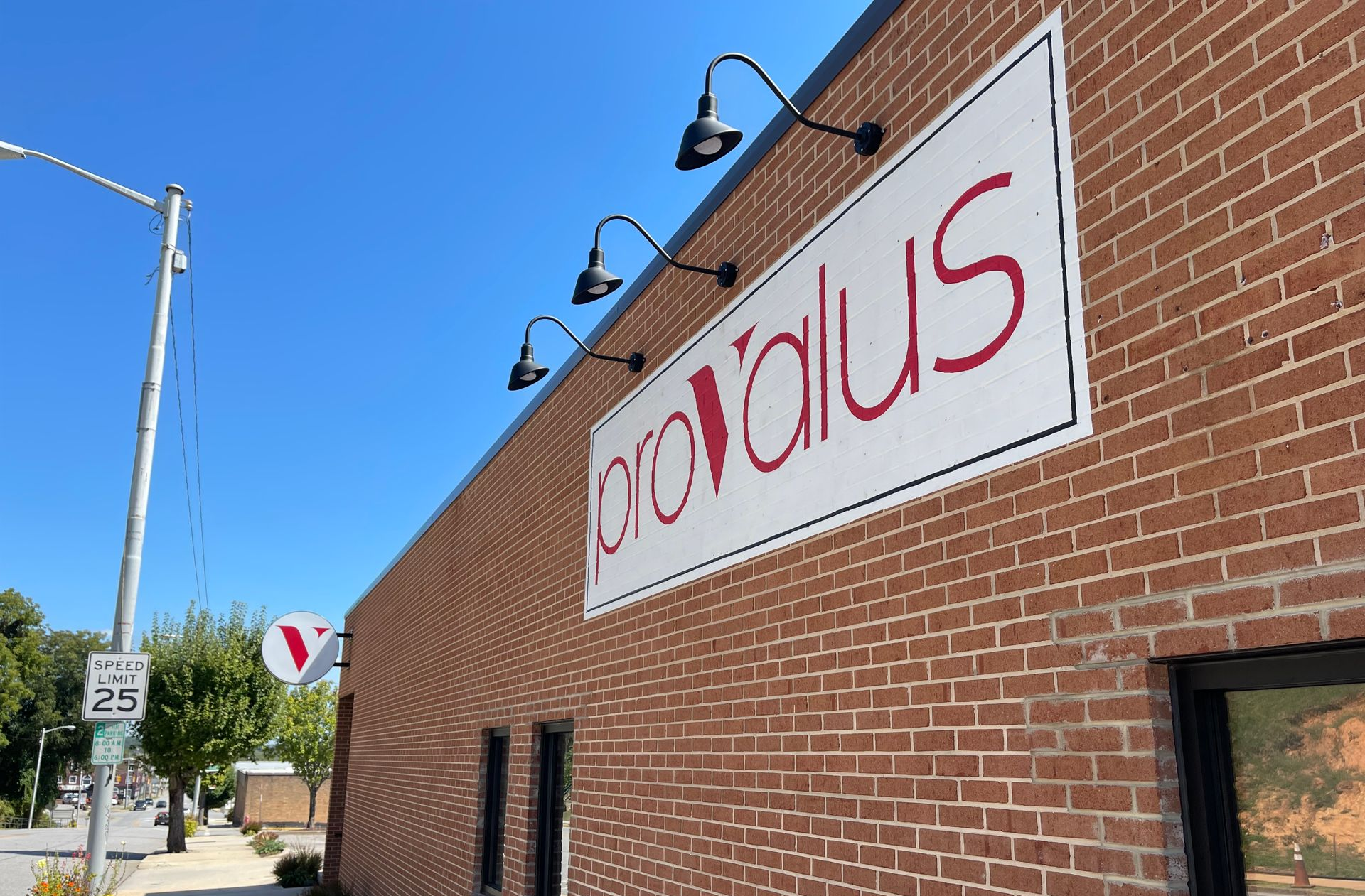 Brick building with a white and red Circalius sign mounted high on the wall under a clear blue sky