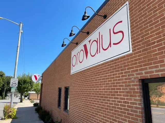 Brick building with a white and red “bravous” sign, black lamps, and a sidewalk by the street.