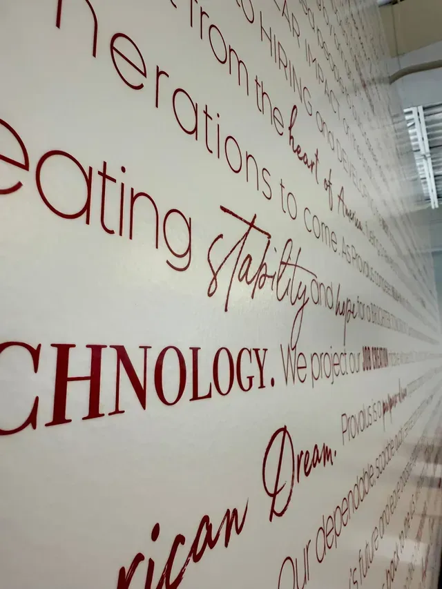 Close-up of a wall with large red typography and words in gray and black.
