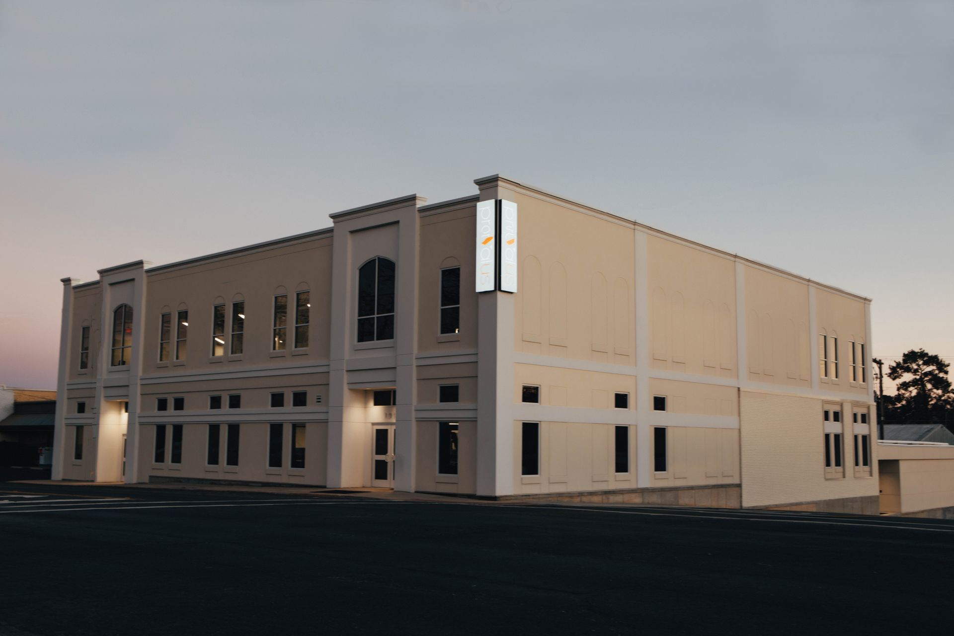 Two-story beige building under construction at dusk, with unfinished exterior walls and windows