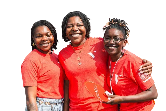 Three people in red shirts smiling and standing together against a white background
