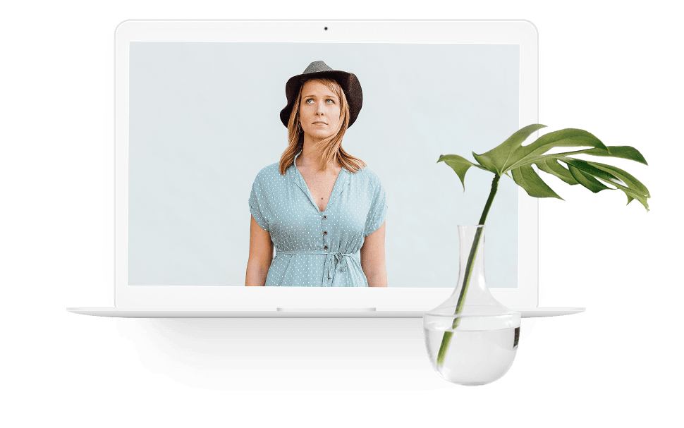 Woman on a laptop screen with a potted plant in the foreground.
