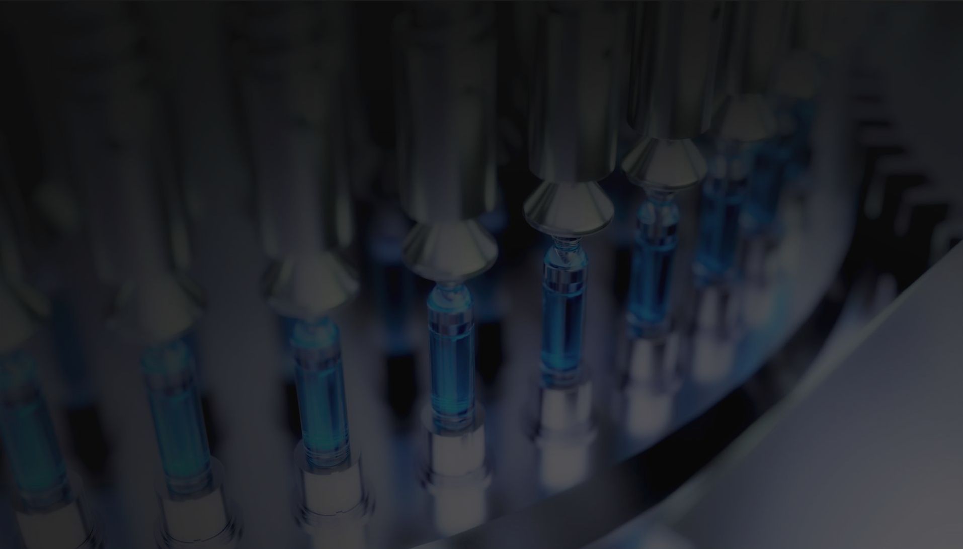 A machine filling a row of small glass vials with a blue liquid in an industrial pharmaceutical setting.