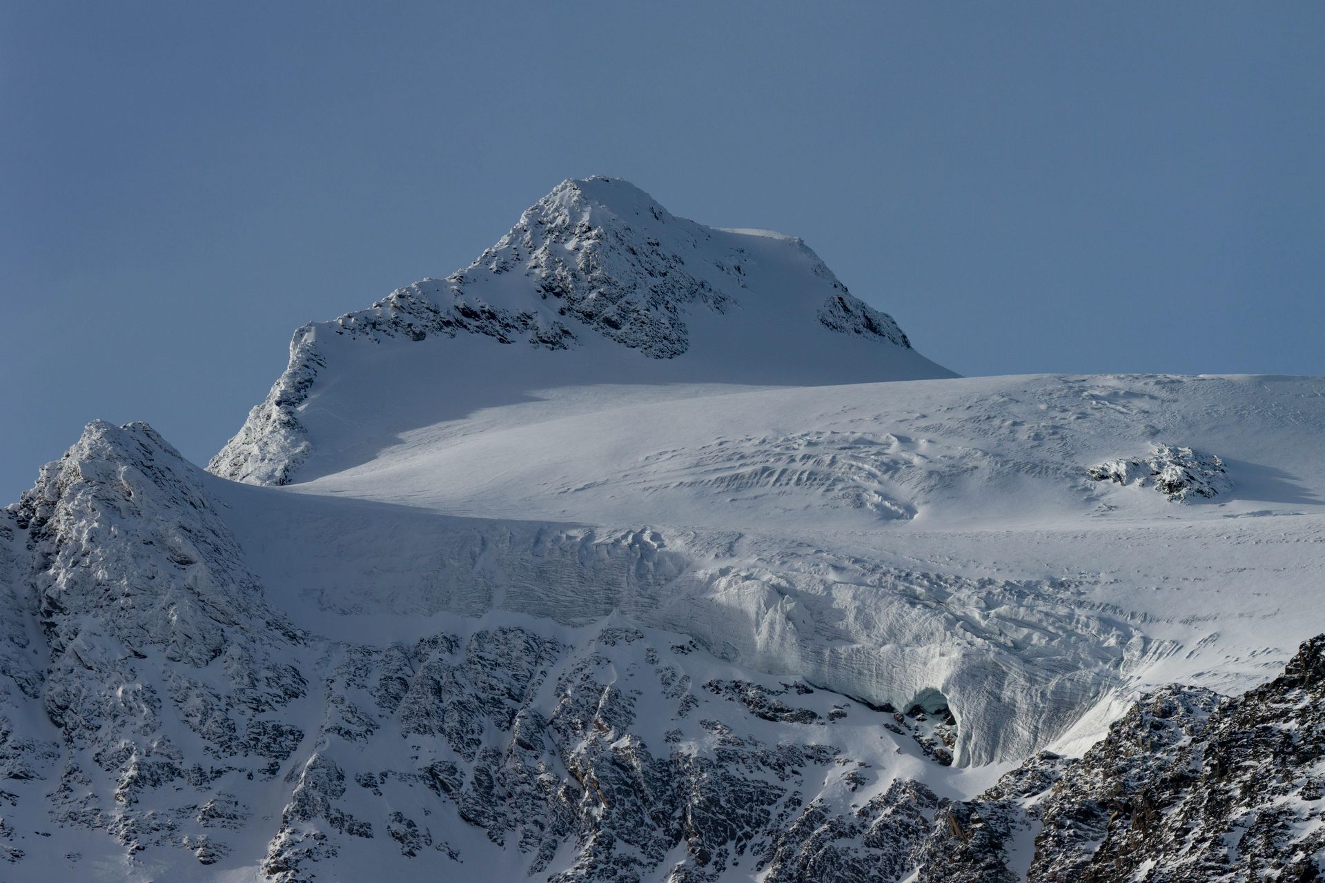 Cima di una montagna innevata contro un cielo terso e azzurro.