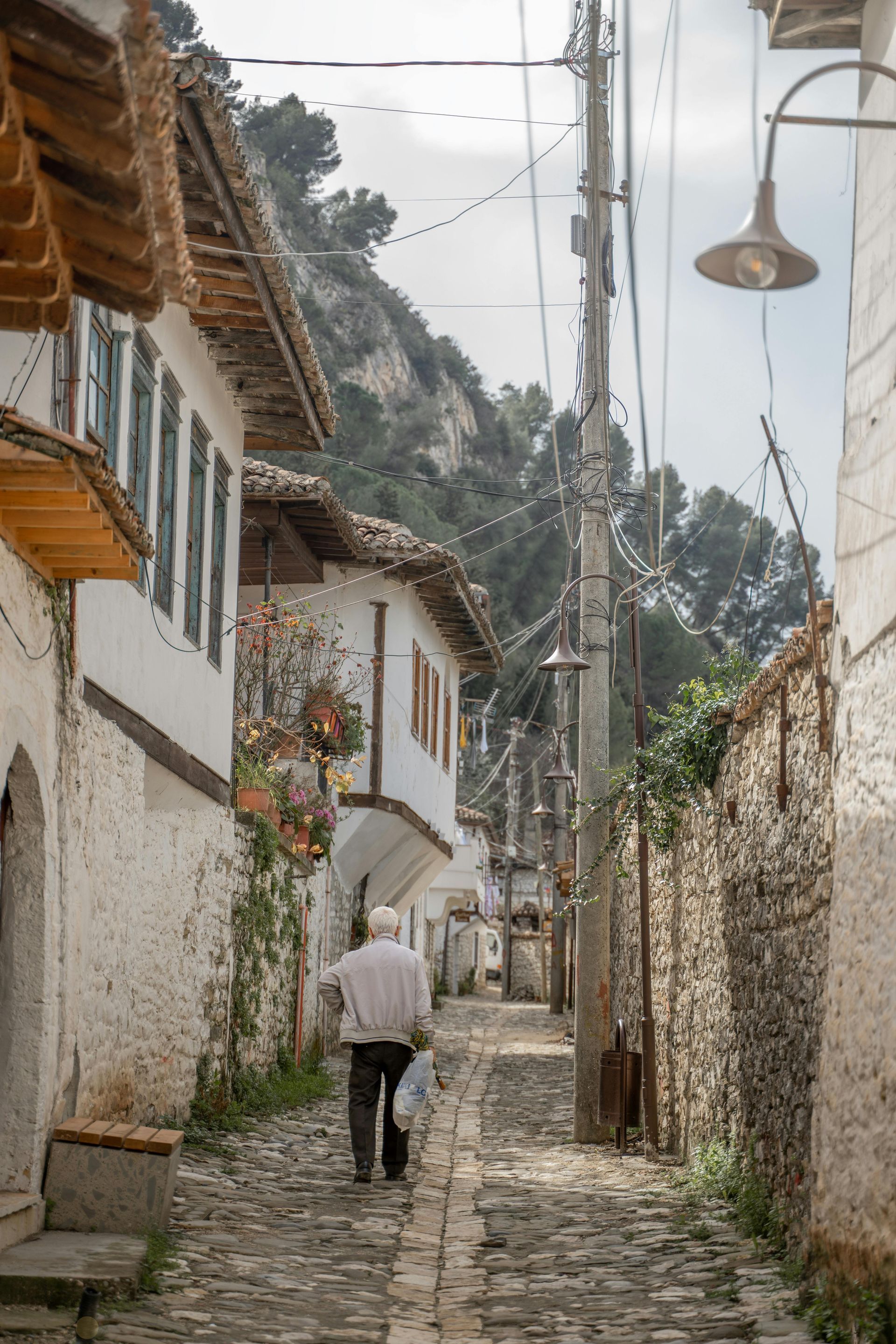 Un uomo sta camminando lungo una strada acciottolata tra due edifici.
