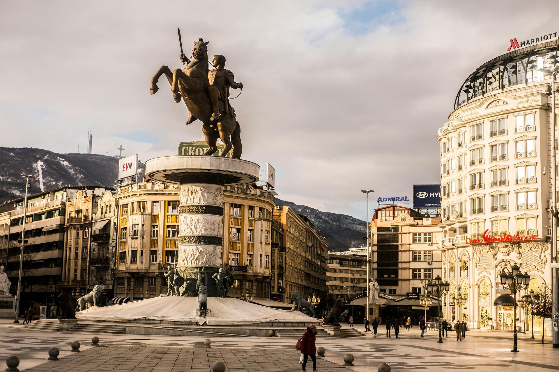 Statua di un uomo a cavallo in una piazza cittadina, circondata da edifici in una giornata nuvolosa.
