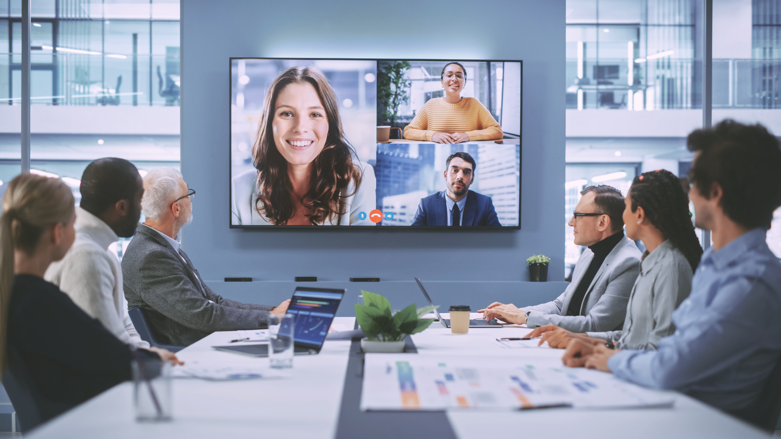 Business meeting in a conference room with a video call on a large wall screen