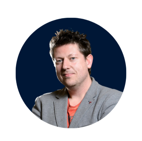 Head-and-shoulders portrait of a person in a gray blazer and orange shirt against a dark blue background