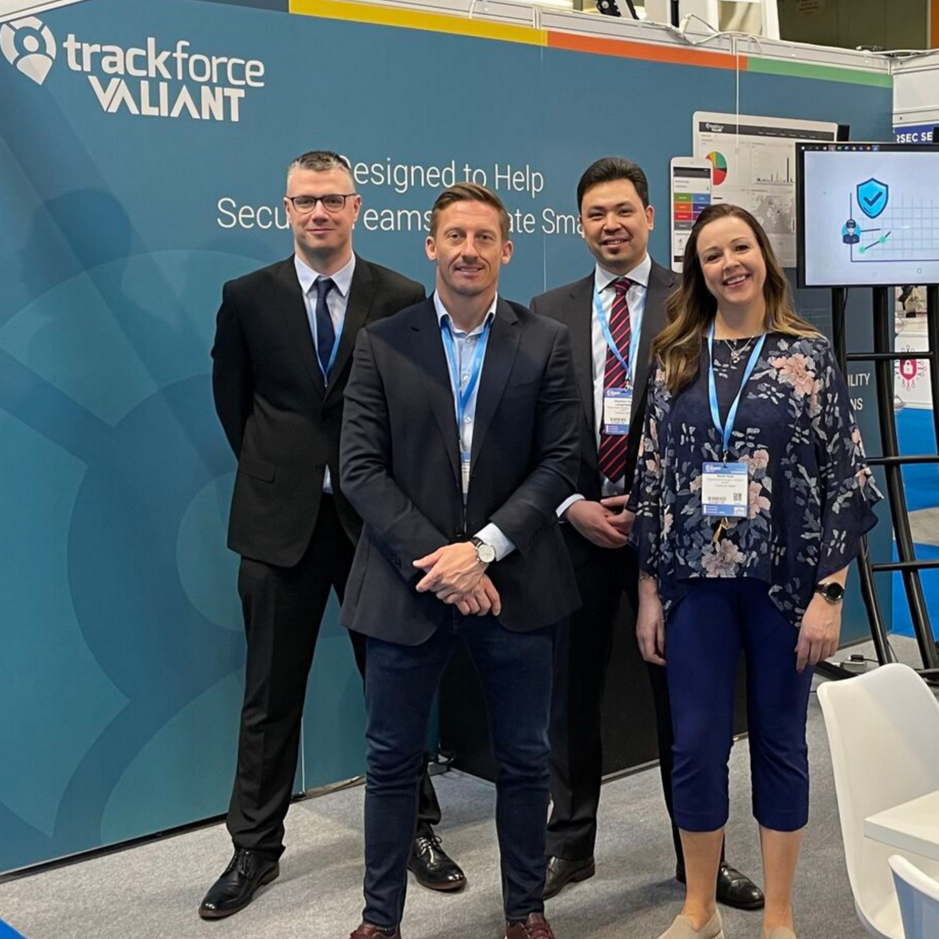 Four people posing at a Trackforce Valiant booth at a trade show.