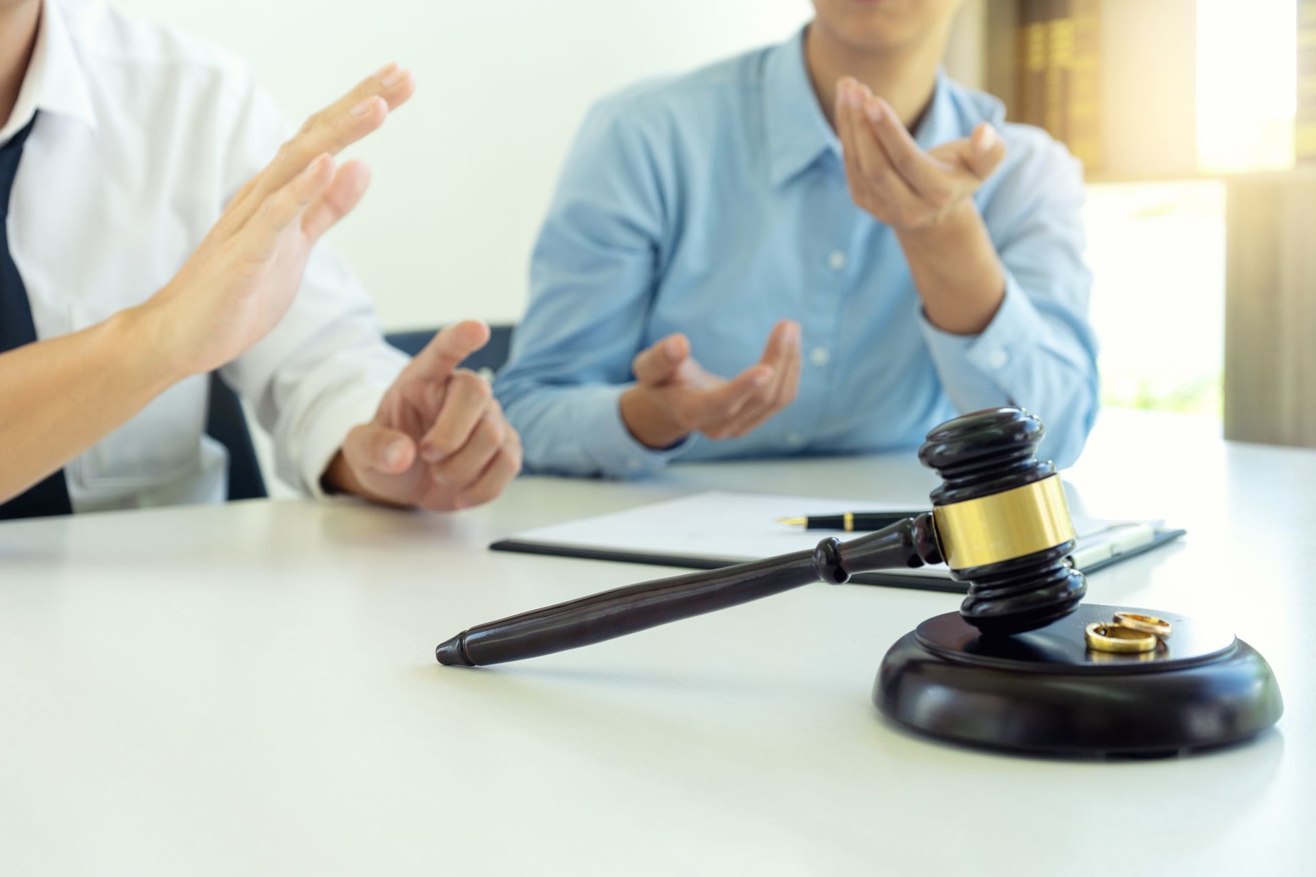 People in a meeting gesturing beside a judge’s gavel on a table