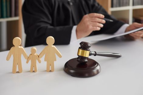 Family figurines beside a judge’s gavel in a custody or divorce legal setting
