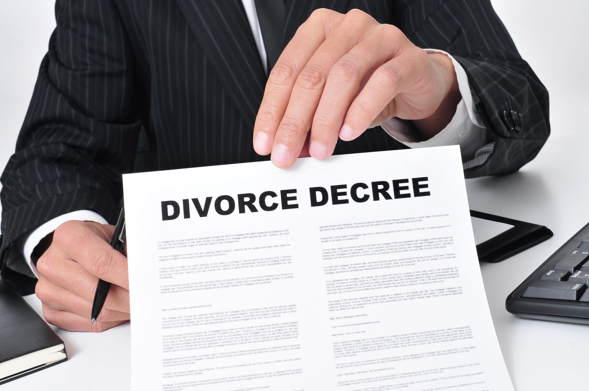 Hands holding a divorce decree document at a desk with a calculator nearby