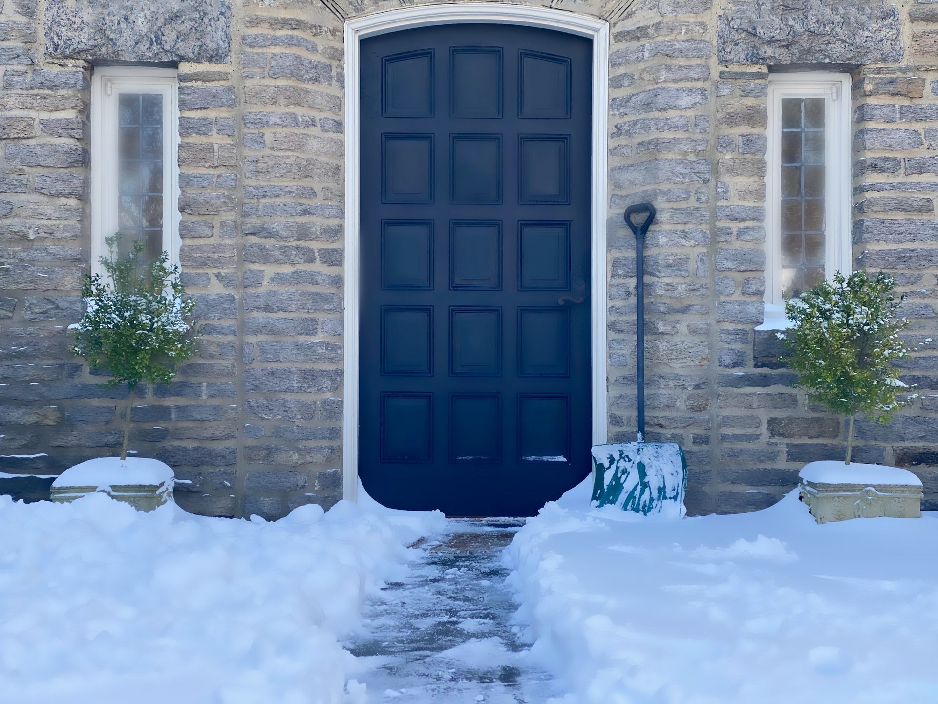 The front door of a brick building is covered in snow.