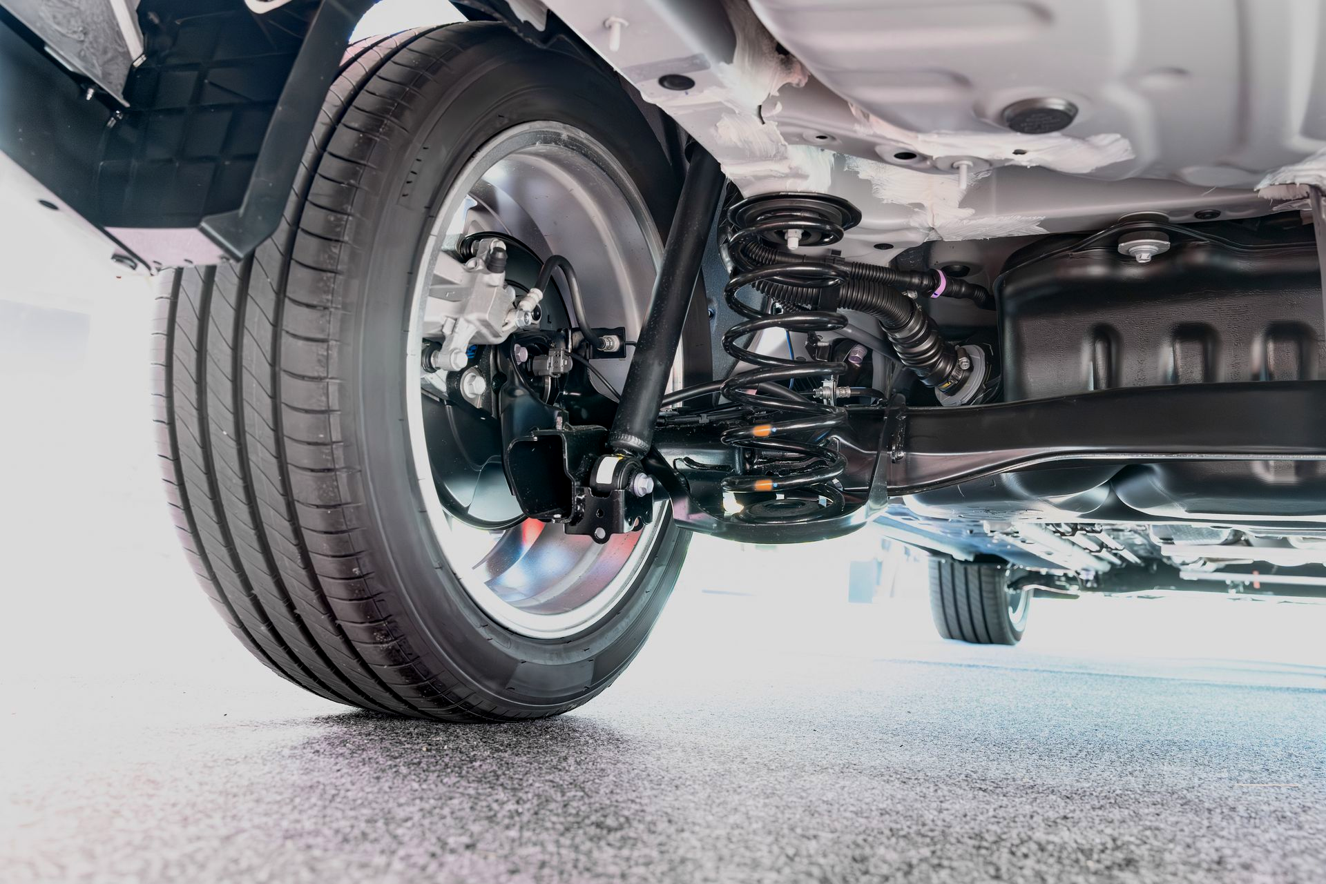 Close-up of a car’s rear suspension and wheel on a raised vehicle underside.