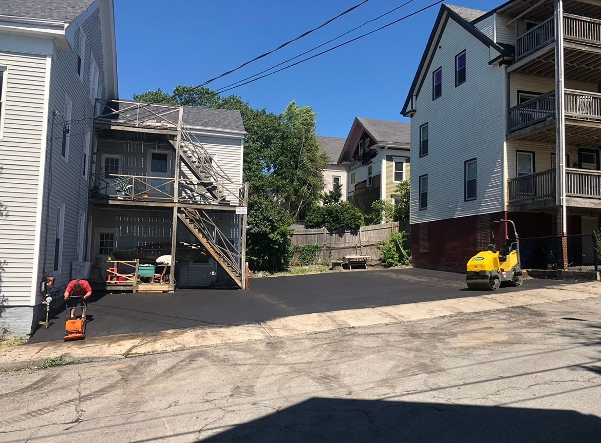 Residential alley with parked cars, two-story houses, and a clear blue sky